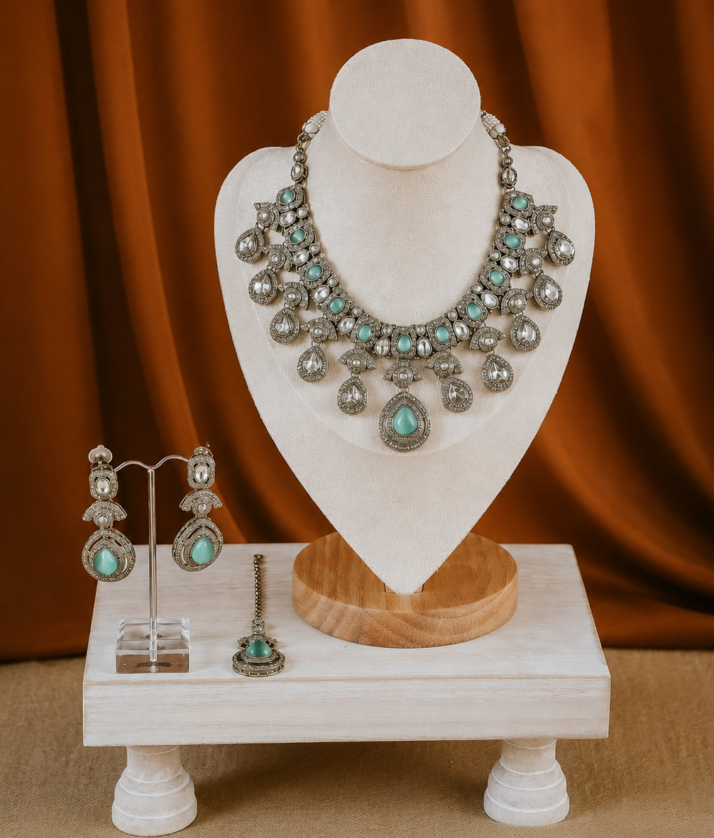 Jewelry set including a necklace and earrings on a white mannequin bust against an orange curtain.