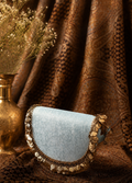 Small round pouch with decorative edge on a textured brown fabric background