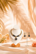 Necklace and earrings on display with a soft, warm background